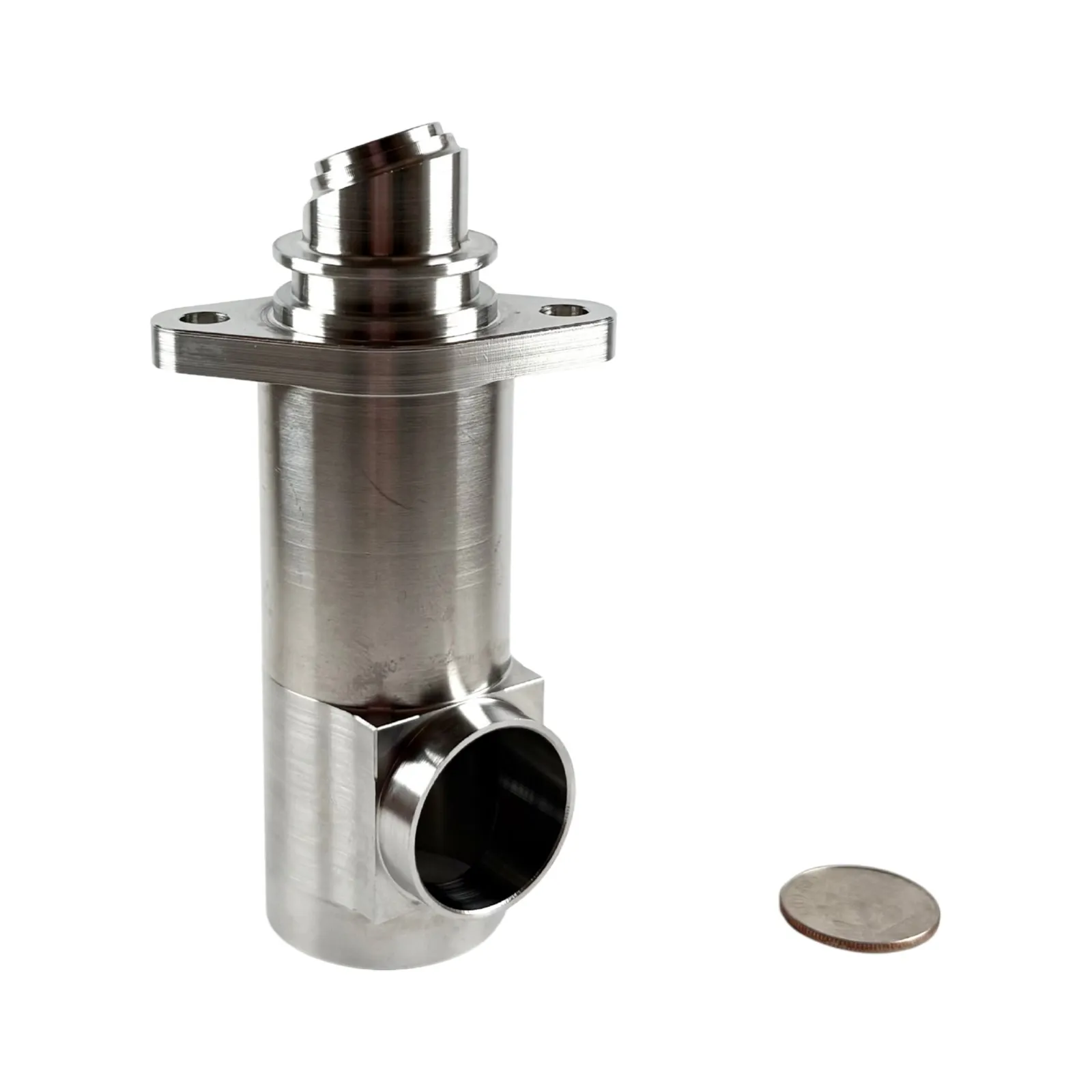 A stainless steel flanged valve body with an angled top fitting and a side outlet bore, shown with a dime for scale