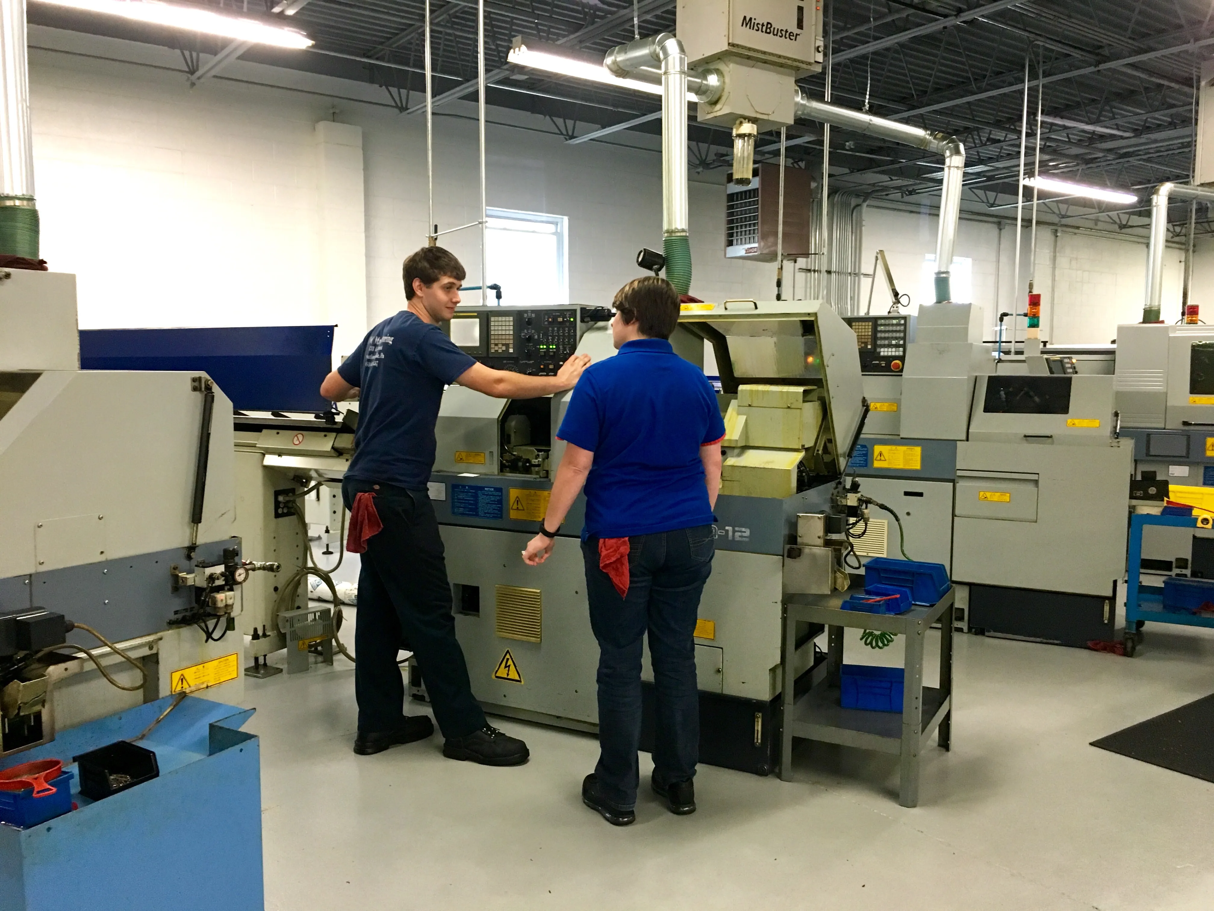 Machinists working at Swiss-type CNC lathes on the shop floor