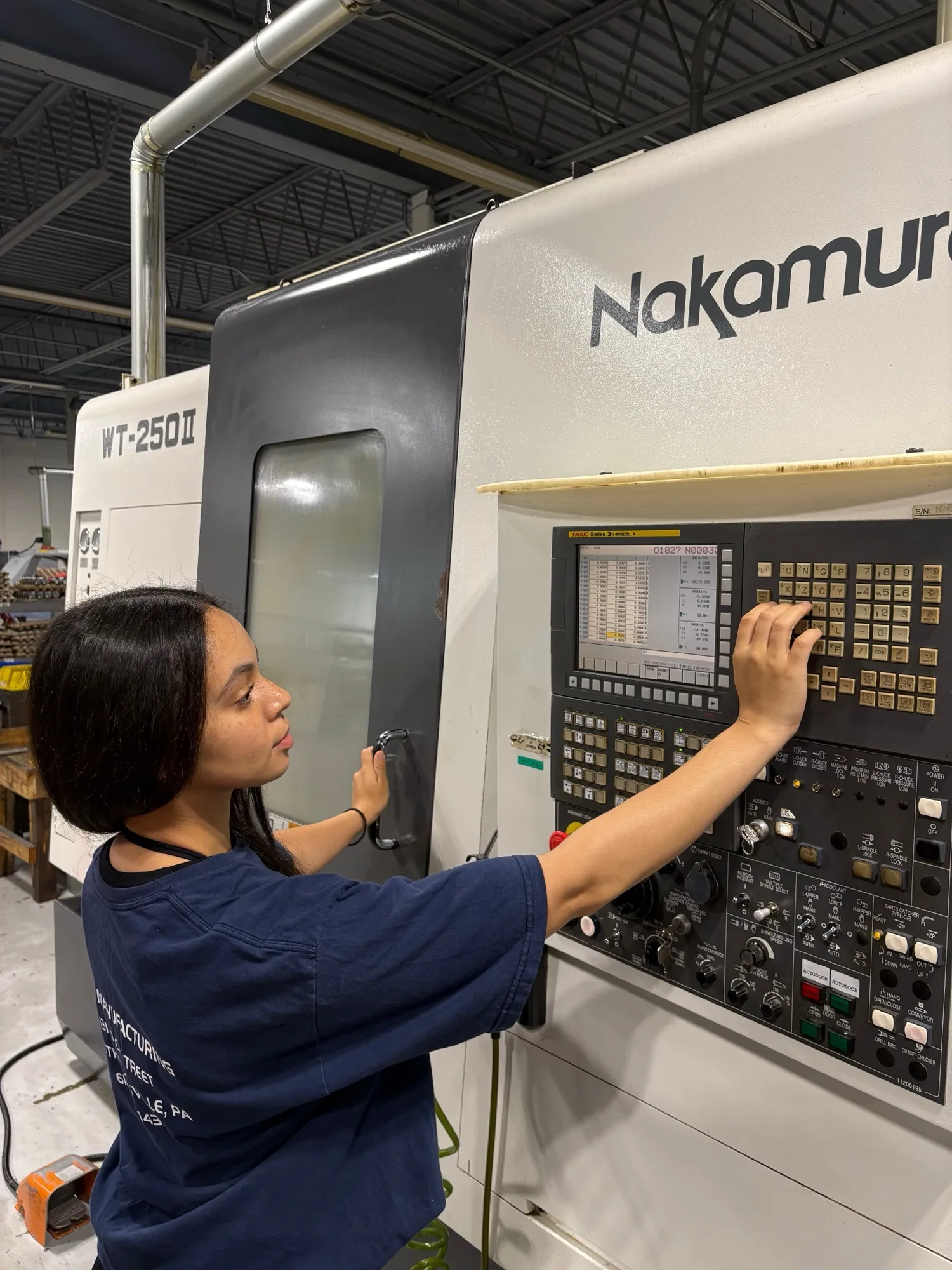 A CNC Manufacturing machinist operating the control panel of a Nakamura-Tome WT-250 mill-turn center