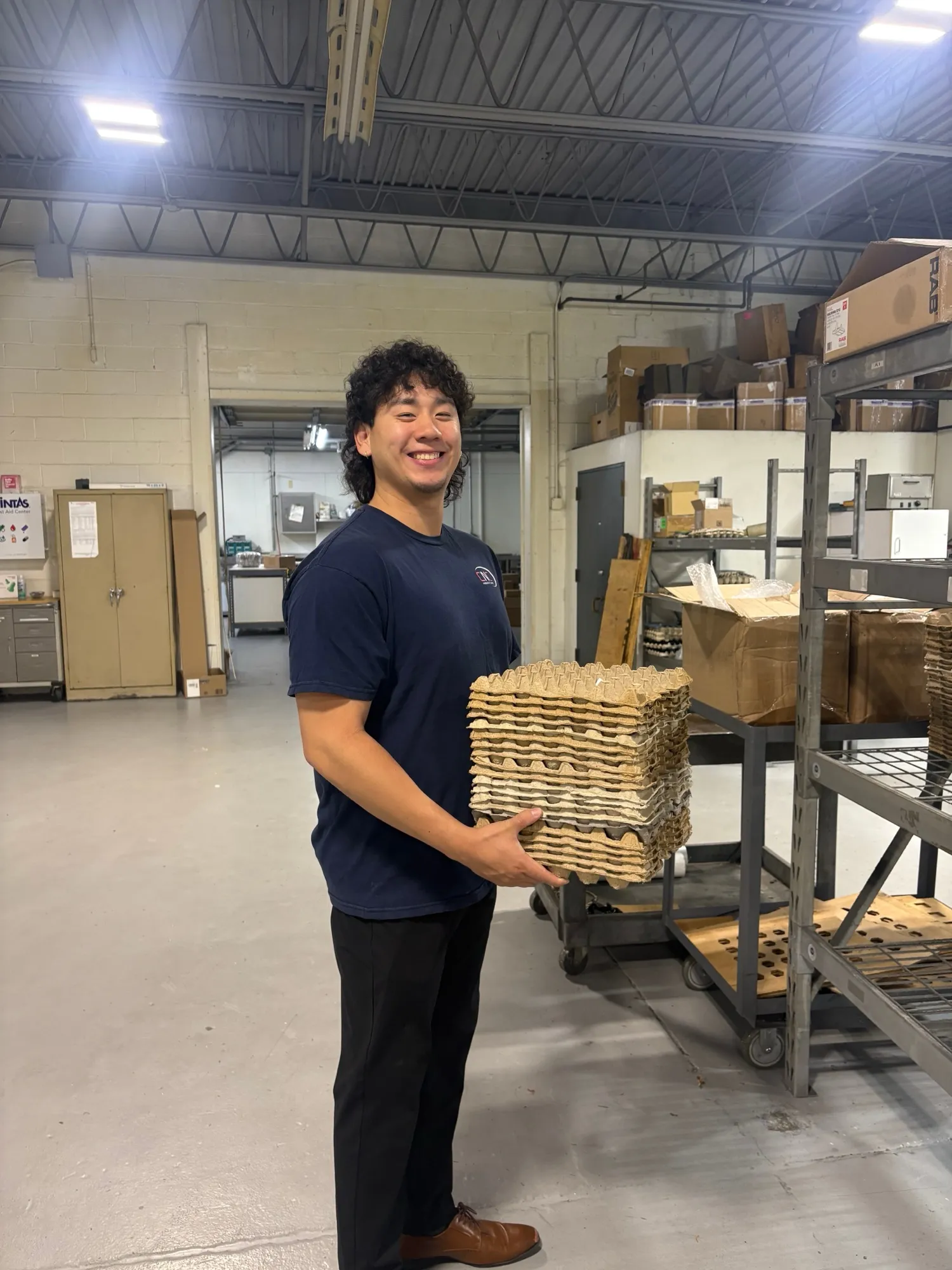 A CNC Manufacturing team member carrying a tray of freshly machined parts on the shop floor